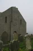 The bell cote was damaged by lightening in the 1990s and removed; the sea is barely visible beyond the gravestones